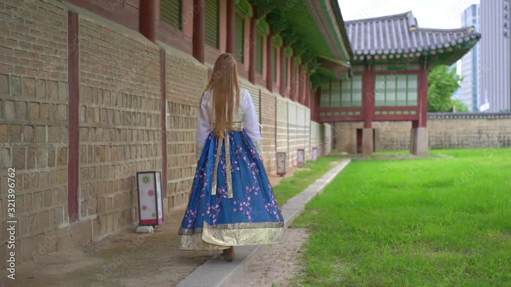 Young woman wearing traditional Korean dress Hanbok visit ancient palace in Seoul, South Korea. Travel to Korea concept. Slowmotion shot Young woman wearing traditional Korean dress Hanbok visit ancient palace in Seoul, South Korea. Travel to Korea concept. Slowmotion shot