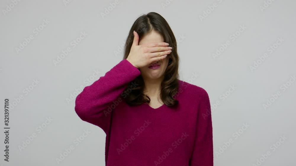 Don't want to watch! Brunette woman in pullover grimacing in disgust and covering eyes with hand, displeased with something shameful awful and ugly. indoor studio shot isolated on gray background Don't want to watch! Brunette woman in pullover grimacing in disgust and covering eyes with hand, displeased with something shameful awful and ugly. indoor studio shot isolated on gray background