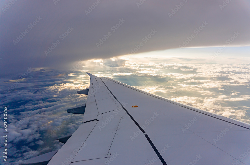 Sky scape view from clear glass window seat to the aircraft wing of the plane, traveling on the clouds and sunshine with blue sky