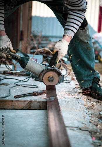 Fototapeta Naklejka Na Ścianę i Meble -  A worker cuts metal at a construction site