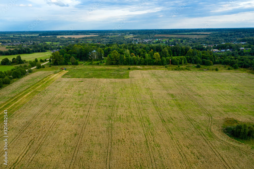 Aerial view of an agricultural field and harvester harvesting in autumn day