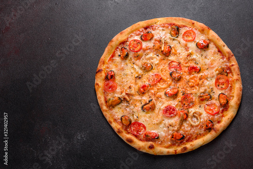 Tasty sliced pizza with seafood and tomato on a concrete background