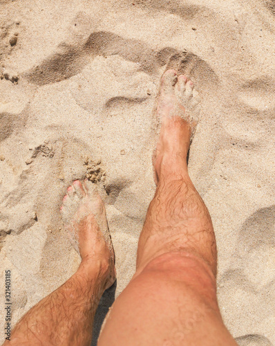 Feet of a man in the hot sand of the desert