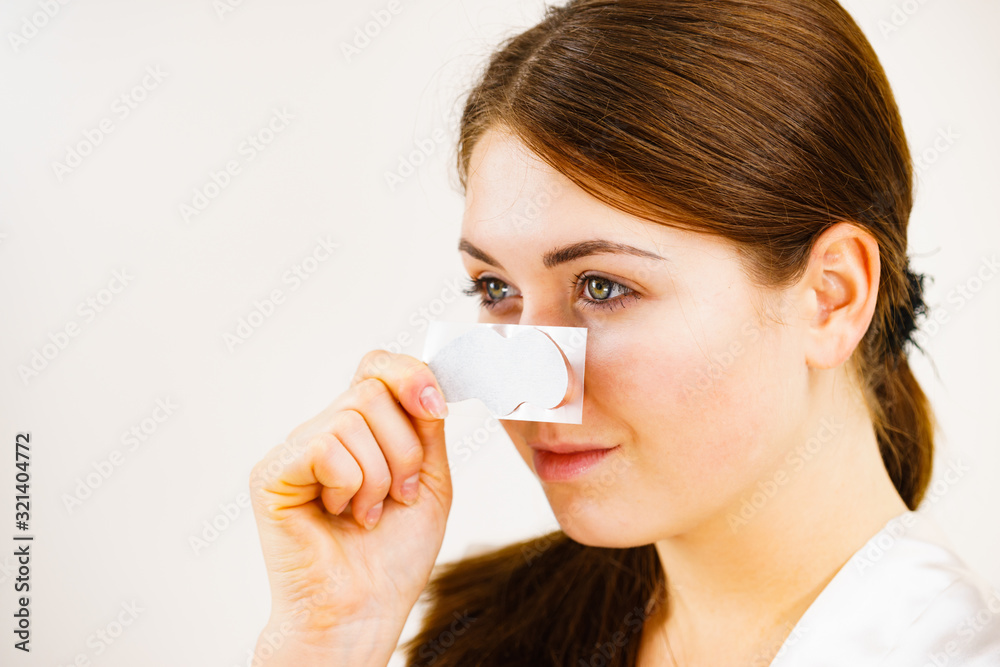 Woman applying pore strips on nose Woman applying pore strips on nose