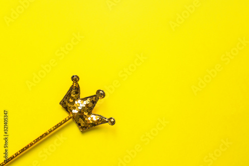 golden sequins crown on bright yellow background. Magic stick. Minimal flat lay, copy space