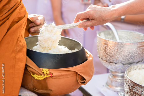 Old woman hand put rice in alms bowl of Buddhist monk on morning photo