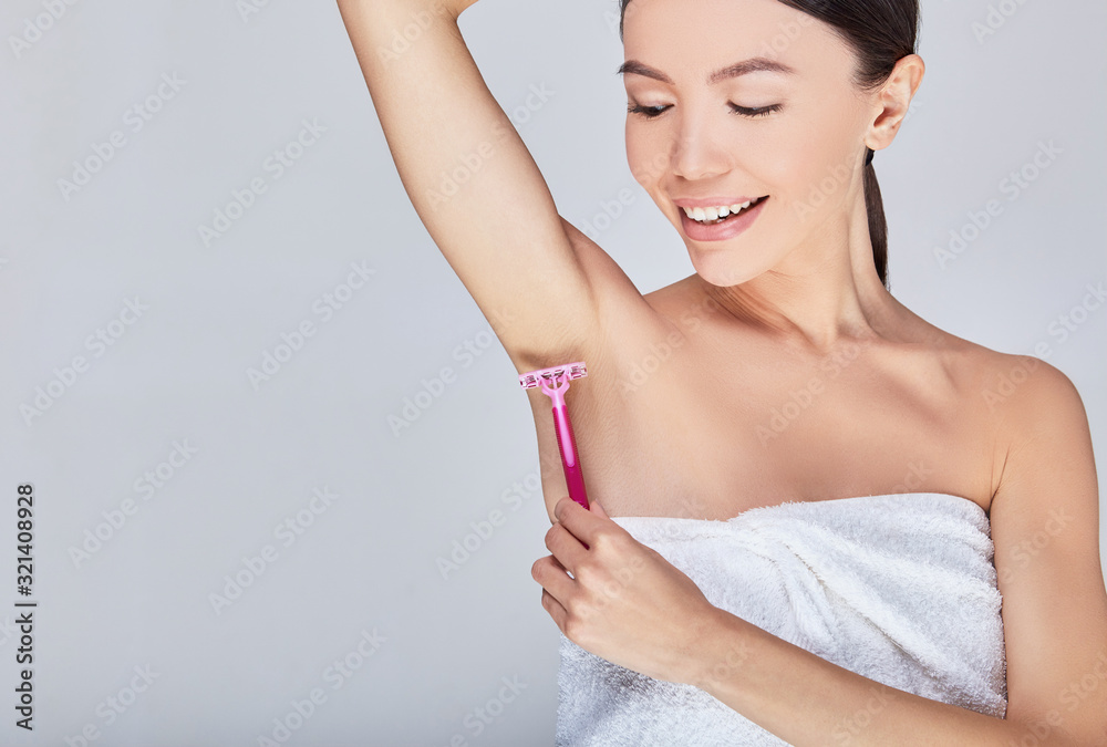 Close-up, cute Asian removes hair from the armpit with a razor.