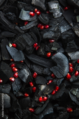 red fruit slices on a dark texture. blank for the menu background. Ripe pomegranate granules. Black charcoal background.