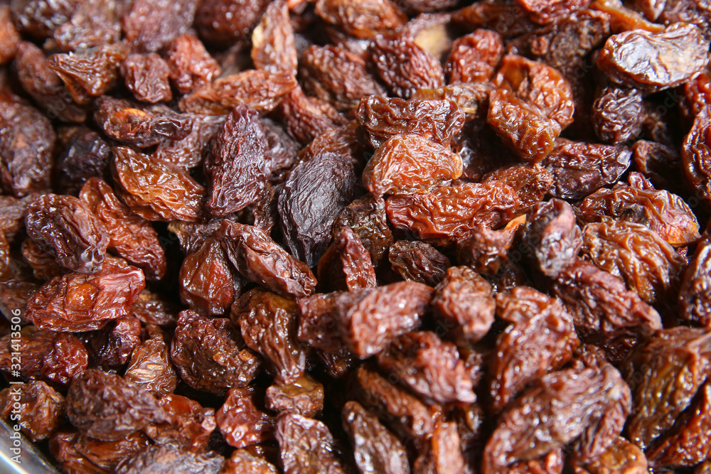 black raisins in the wooden bowl. Sweet dry raisins close-up shot for background . Many Raisins for background grape raisin texture .