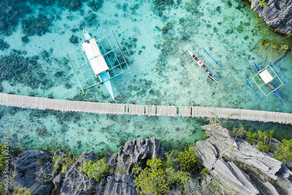 View from above, stunning aerial view of a Bangka floating on a turquoise, crystal clear sea. A Bangka is a double outrigger canoe native of the Philippines. Coron Island, Palawan, Philippines.