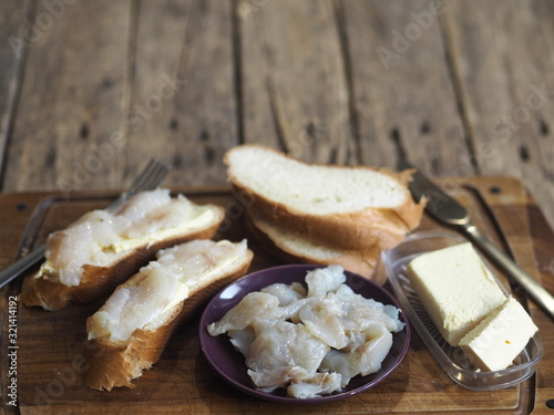 Breakfast, lunch, snack. Sandwiches with butter and freshly salted fish pike on a cutting kitchen board. XE fish salad. Wooden background.