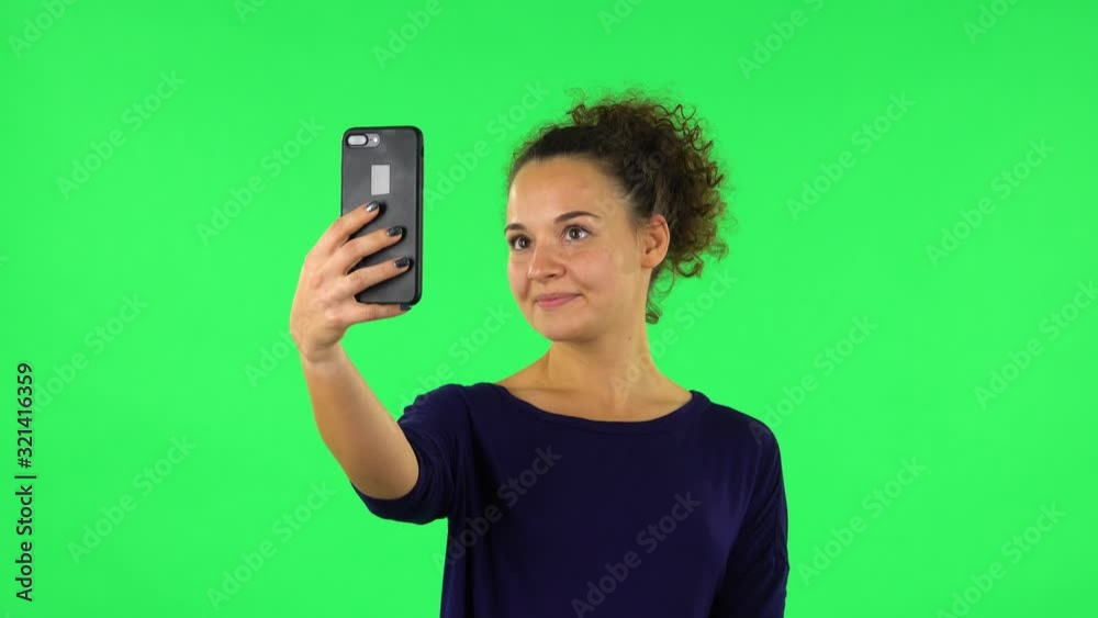 Portrait of curly woman smiling woman texting on her phone . Green screen Portrait of curly woman smiling woman texting on her phone . Green screen