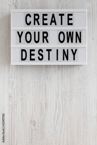 'Create your own destiny' words on a modern board on a white wooden background, top view. Overhead, from above, flat lay. Copy space.