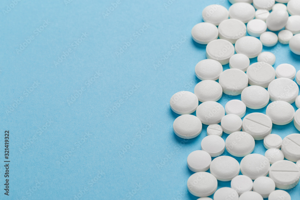 scattered white pills on a blue table. Layout for special offers such as advertising or other ideas. The concept of medicine, pharmacy and healthcare. Space for copy. flat lay for text or logo.