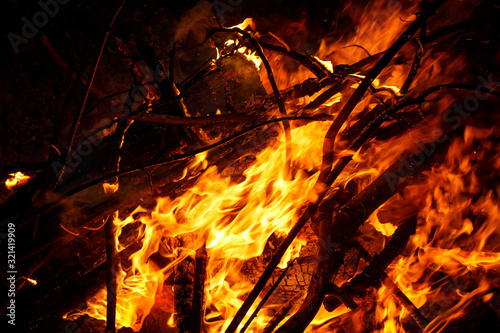 A pile of branches engulfed in the flames of a fire, a bright fire on a black background