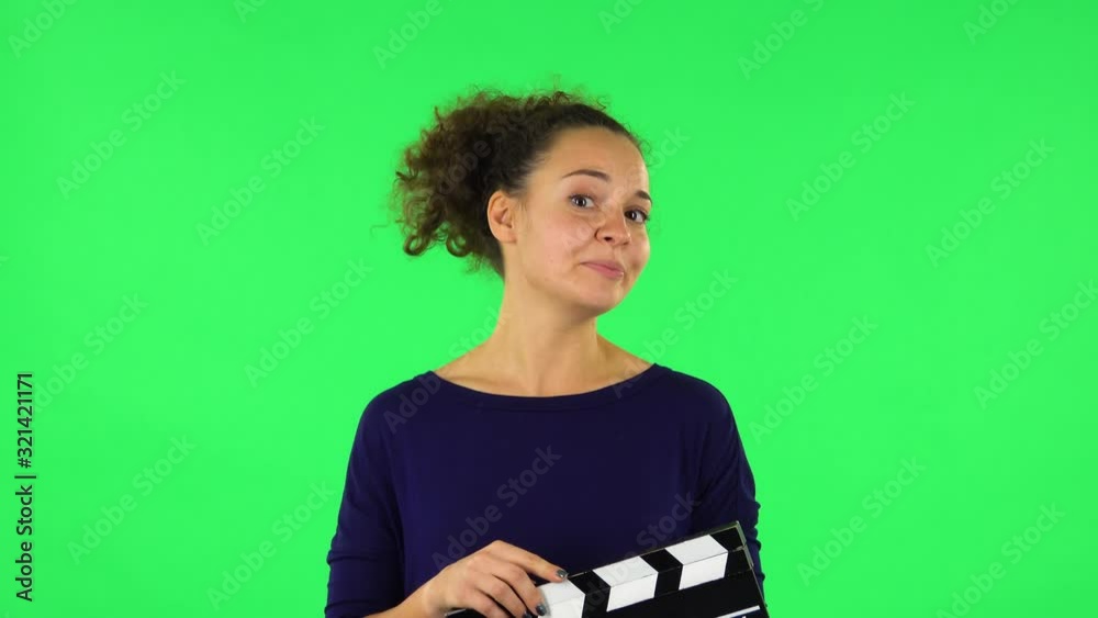 Portrait of curly woman is holding a movie in her hands. Green screen