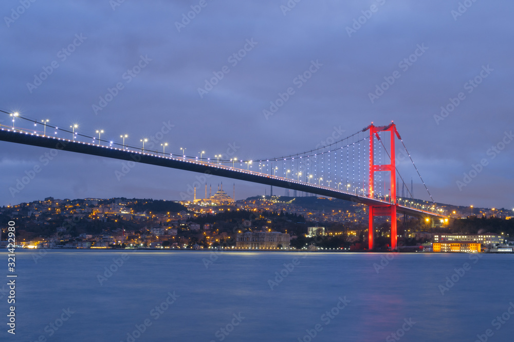 Dusk over the First Bosporus Bridge Crossing the Bosphorus or Bosporus Straits Istanbul Turkey. Büyük Çamlıca Camii Mosque and Beylerbeyi  Palace are visible .