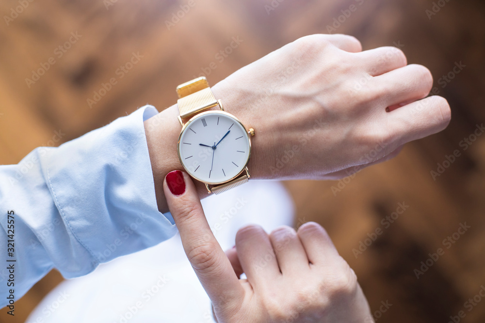 Young woman checking the time on watch - obrazy, fototapety, plakaty 