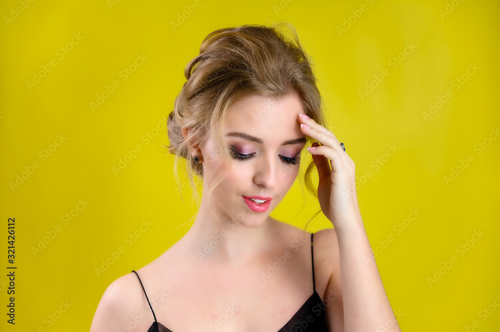 The concept of cosmetics, fashion and style. Glamorous beauty portrait of a pretty blonde model with excellent makeup and a beautiful hairstyle on a yellow background in the studio. The concept of cosmetics, fashion and style. Glamorous beauty portrait of a pretty blonde model with excellent makeup and a beautiful hairstyle on a yellow background in the studio.
