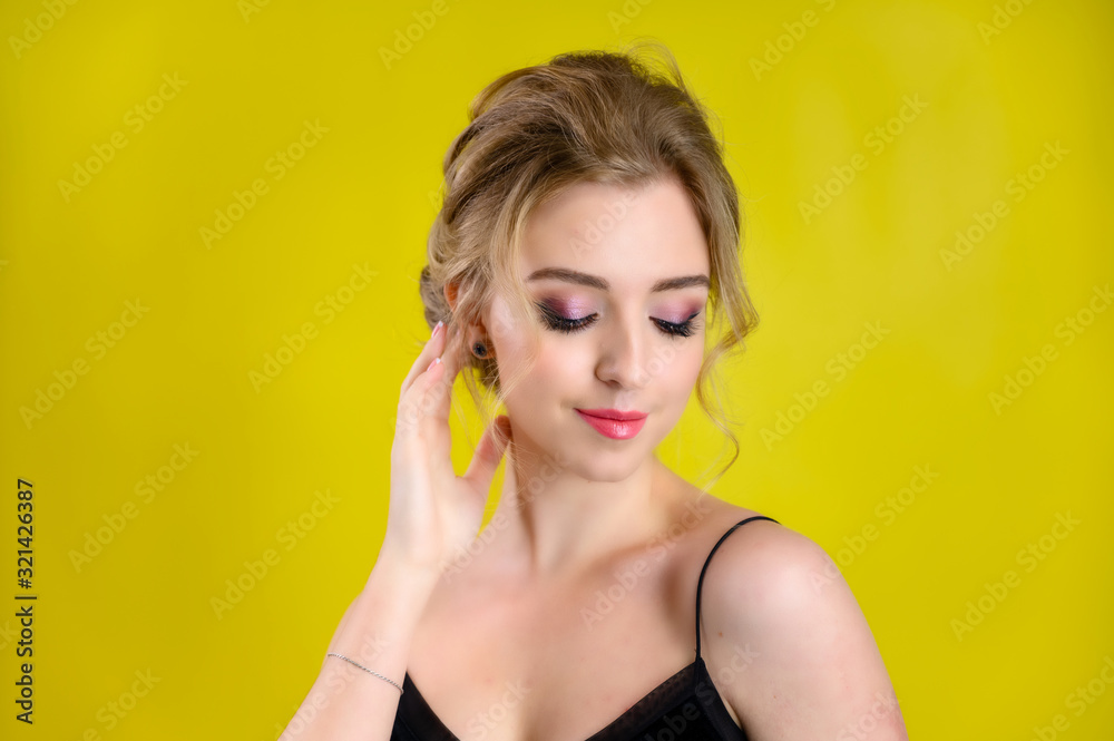 Glamorous beauty portrait of a pretty blonde model with excellent makeup and a beautiful hairstyle on a yellow background in the studio. The concept of cosmetics, fashion and style. Glamorous beauty portrait of a pretty blonde model with excellent makeup and a beautiful hairstyle on a yellow background in the studio. The concept of cosmetics, fashion and style.