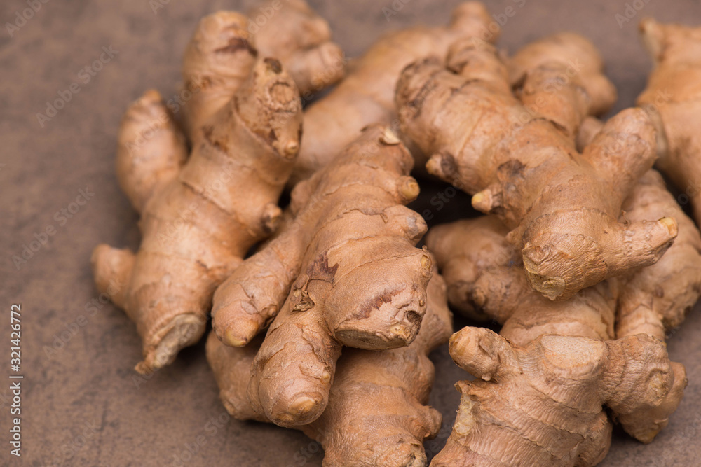 Fresh ginger roots on a brown textured background, empty copy space Fresh ginger roots on a brown textured background, empty copy space