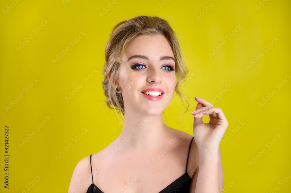 Glamorous beauty front view portrait of a pretty blonde model with excellent make-up and beautiful hairstyle on a yellow background in the studio. The concept of cosmetics, fashion and style. Glamorous beauty front view portrait of a pretty blonde model with excellent make-up and beautiful hairstyle on a yellow background in the studio. The concept of cosmetics, fashion and style.