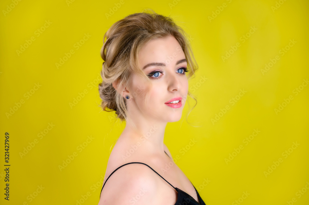 Glamorous beauty portrait side view of a pretty blonde model with excellent makeup and a beautiful hairstyle on a yellow background in the studio. The concept of cosmetics, fashion and style. Glamorous beauty portrait side view of a pretty blonde model with excellent makeup and a beautiful hairstyle on a yellow background in the studio. The concept of cosmetics, fashion and style.