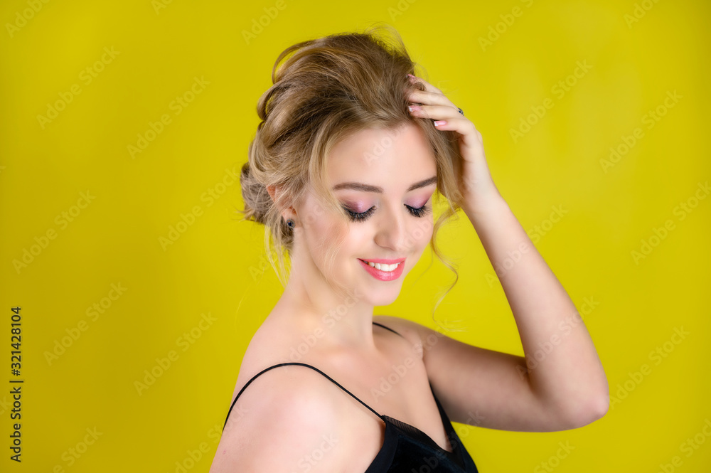 Glamorous beauty portrait side view of a pretty blonde model with excellent makeup and a beautiful hairstyle on a yellow background in the studio. The concept of cosmetics, fashion and style. Glamorous beauty portrait side view of a pretty blonde model with excellent makeup and a beautiful hairstyle on a yellow background in the studio. The concept of cosmetics, fashion and style.