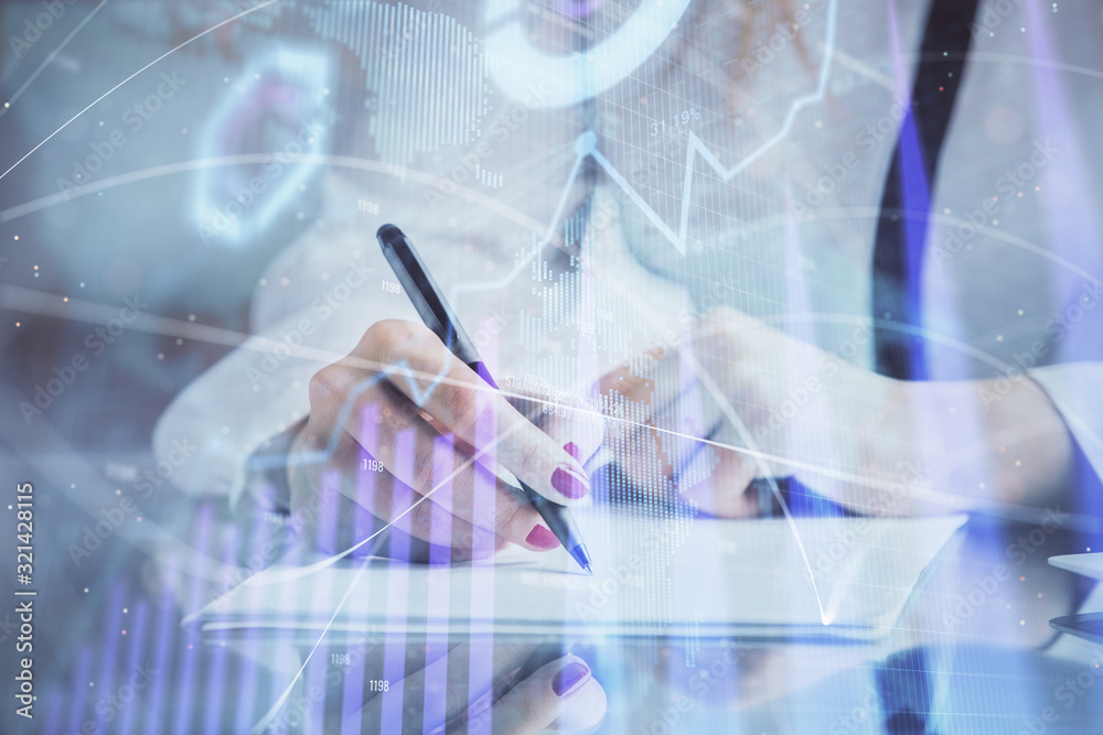 Double exposure of hands making notes with forex chart huds. Stock market concept.