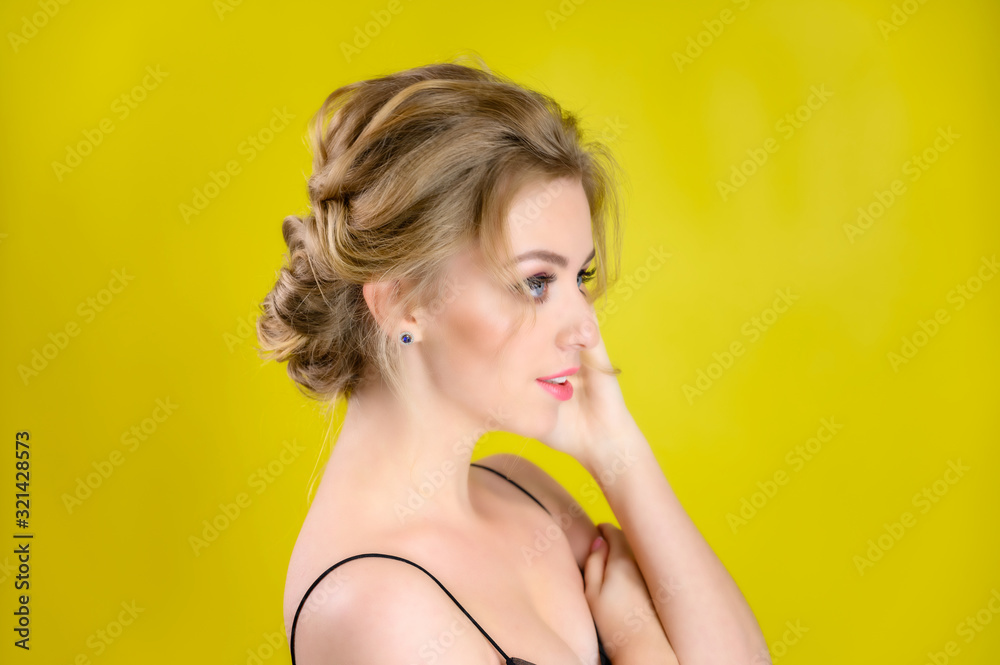 Glamorous beauty portrait side view of a pretty blonde model with excellent makeup and a beautiful hairstyle on a yellow background in the studio. The concept of cosmetics, fashion and style. Glamorous beauty portrait side view of a pretty blonde model with excellent makeup and a beautiful hairstyle on a yellow background in the studio. The concept of cosmetics, fashion and style.