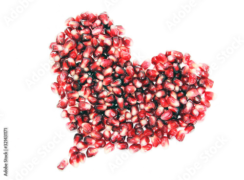 Heart shaped ruby ​​fresh pomegranate seeds on white background