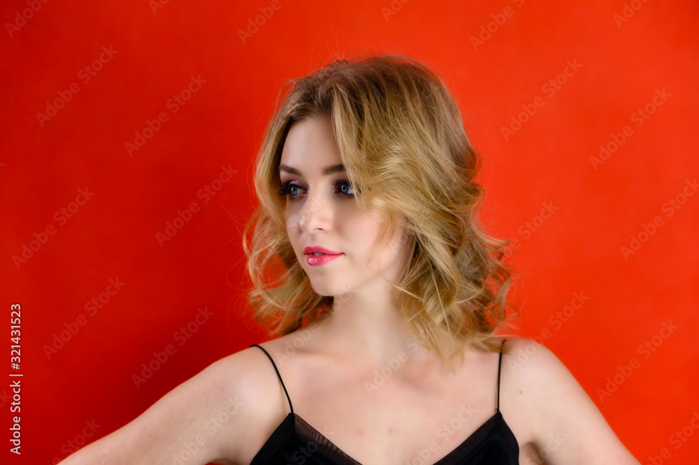The concept of cosmetics, fashion and style. Glamorous beauty front view portrait of a pretty model with blond hair with great makeup and a beautiful hairstyle on a red background in the studio. The concept of cosmetics, fashion and style. Glamorous beauty front view portrait of a pretty model with blond hair with great makeup and a beautiful hairstyle on a red background in the studio.