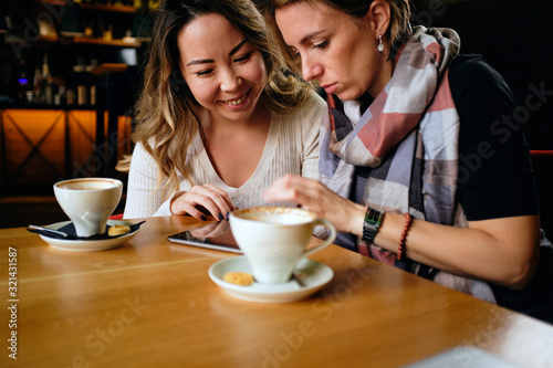 Two female friends in a cafe having coffee, smiling and chatting