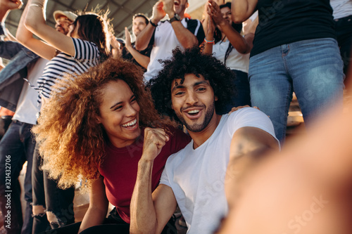 Fototapeta Naklejka Na Ścianę i Meble -  Couple of spectators taking selfie in stadium