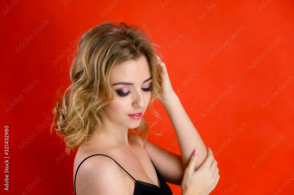Glamorous beauty portrait side view of a pretty model with blond hair with great makeup and a beautiful hairstyle on a red background in the studio. The concept of cosmetics, fashion and style. Glamorous beauty portrait side view of a pretty model with blond hair with great makeup and a beautiful hairstyle on a red background in the studio. The concept of cosmetics, fashion and style.