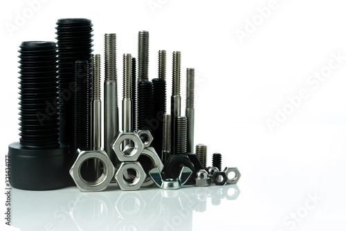 Metal bolts and nuts on white background. Fasteners equipment. Hardware tools. Stud bolt, hex nuts, and hex head bolts in workshop. Threaded fastener use in automotive engineering. Hexagonal bolt.