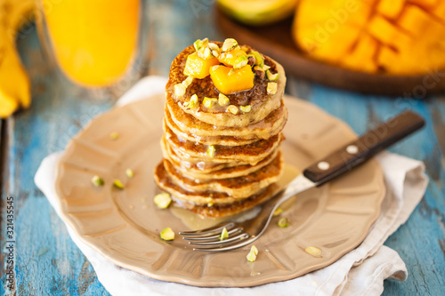 A stack of vegan pancakes with mango anf orange juice