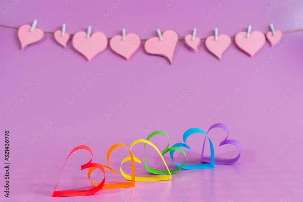 Love hearts with the colors of LGBT on pink background.