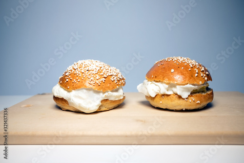 A traditional Scandinavian shrovetide buns with whipped cream on white table. Shrovetide buns are classic delicacies for Shorevetide Sunday and Tuesday. photo