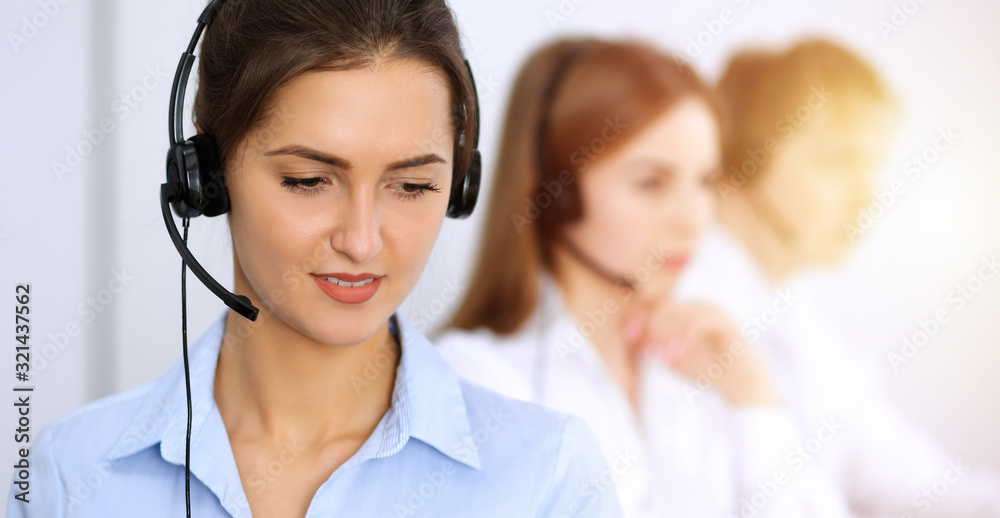 Call center. Focus on beautiful business woman using headset in sunny office Call center. Focus on beautiful business woman using headset in sunny office