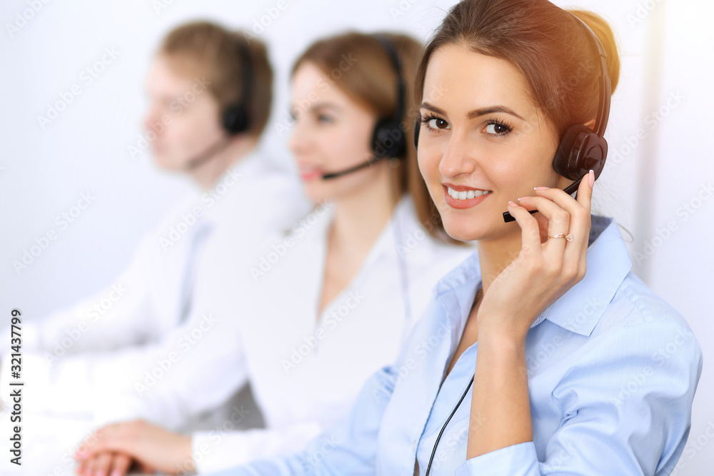 Call center. Focus on beautiful business woman using headset in sunny office Call center. Focus on beautiful business woman using headset in sunny office