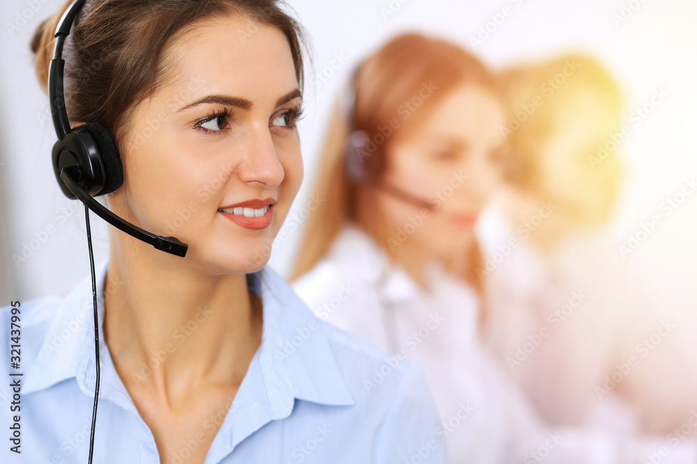 Call center. Focus on beautiful business woman using headset in sunny office Call center. Focus on beautiful business woman using headset in sunny office
