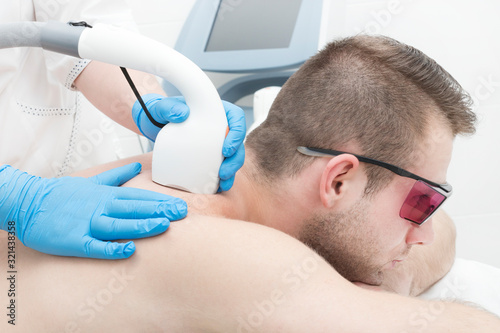 Laser hair removal procedure for a man in a beauty salon.