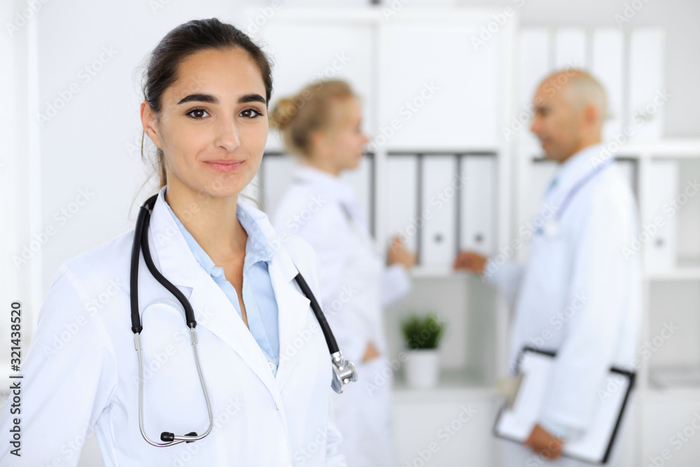 Doctor woman in clinic with colleagues at the background. Hispanic or latin american staff in medicine Doctor woman in clinic with colleagues at the background. Hispanic or latin american staff in medicine