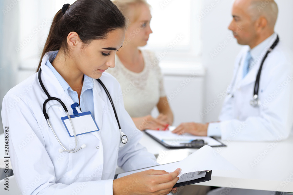 Doctor woman in clinic with colleagues at the background. Hispanic or latin american staff in medicine Doctor woman in clinic with colleagues at the background. Hispanic or latin american staff in medicine