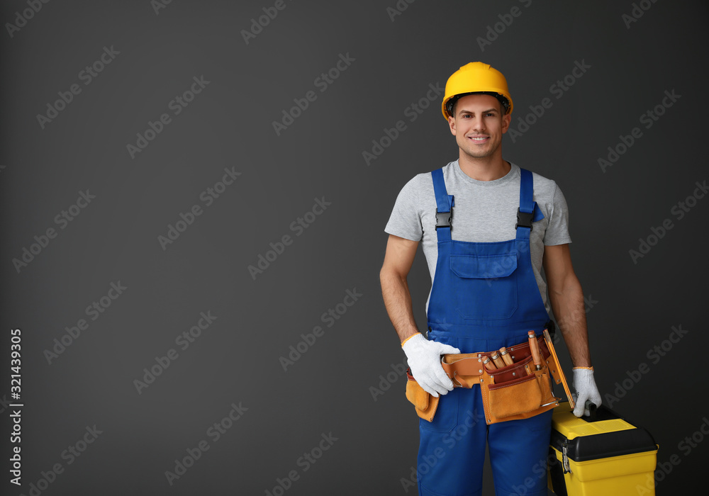 Handsome carpenter with tool box on dark background. Space for text Handsome carpenter with tool box on dark background. Space for text