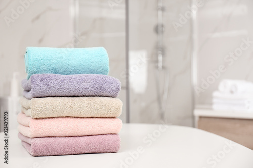 Stack of color towels on white table in bathroom. Space for text