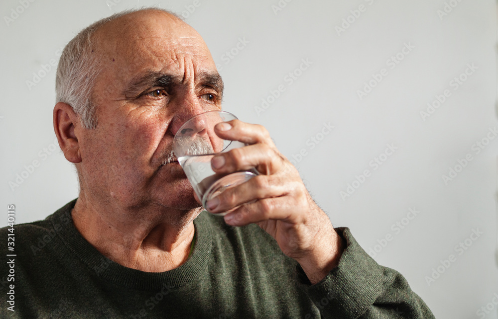 Elderly man taking medication with water in a close up portrait Elderly man taking medication with water in a close up portrait