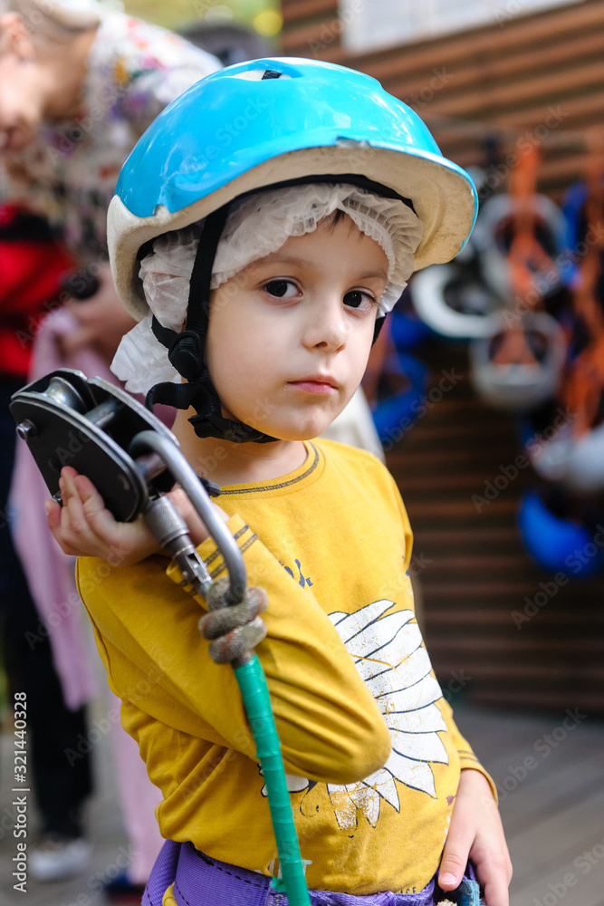 Portrait of a five-year-old boy in a climbing helmet in a steam park. Concept - safety in a rope park. Portrait of a five-year-old boy in a climbing helmet in a steam park. Concept - safety in a rope park.