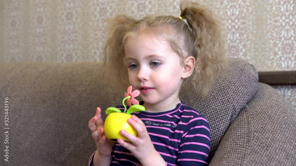 Little girl with a flower toy. Girl sniffs a toy flower. Flower moves from the solar battery. Little girl with a flower toy. Girl sniffs a toy flower. Flower moves from the solar battery.